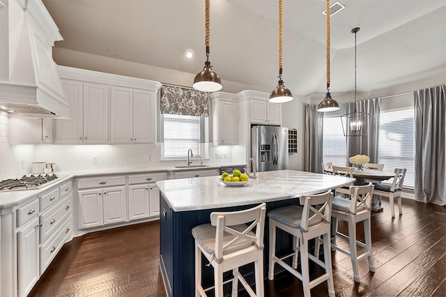 kitchen with visible vents, lofted ceiling, stainless steel appliances, premium range hood, and a sink