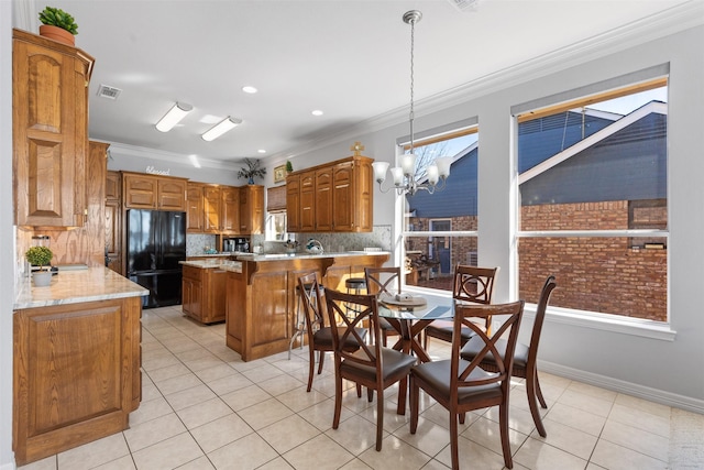 kitchen with a breakfast bar, black fridge, decorative light fixtures, a chandelier, and ornamental molding