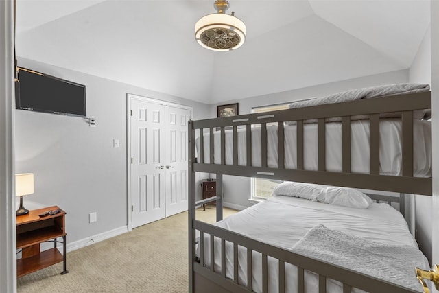 carpeted bedroom with lofted ceiling and a closet