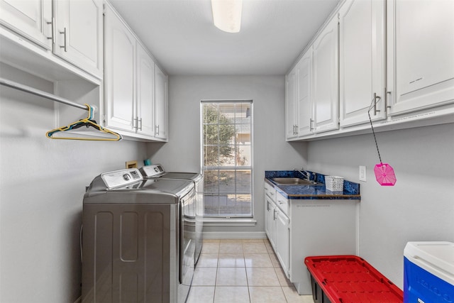 clothes washing area featuring cabinets, sink, light tile patterned floors, and washing machine and clothes dryer