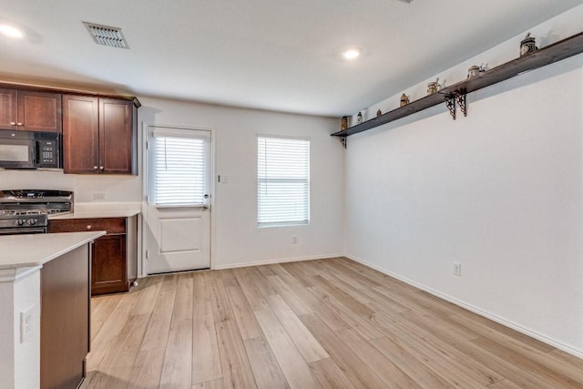 kitchen with dark brown cabinets, range with gas cooktop, and light hardwood / wood-style floors