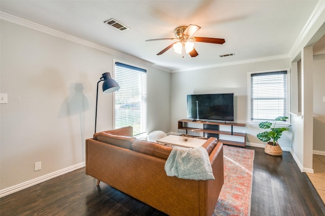 living room featuring dark wood-type flooring, ornamental molding, and a healthy amount of sunlight