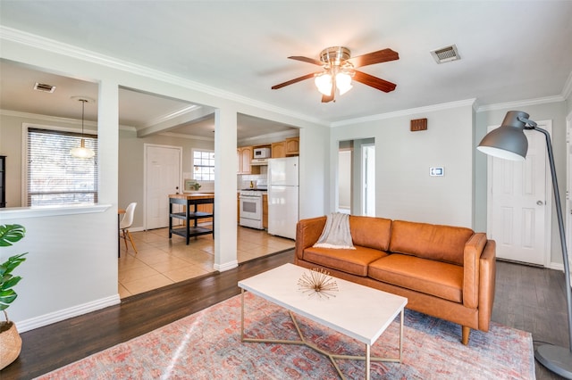 living room with ornamental molding, light hardwood / wood-style floors, and ceiling fan