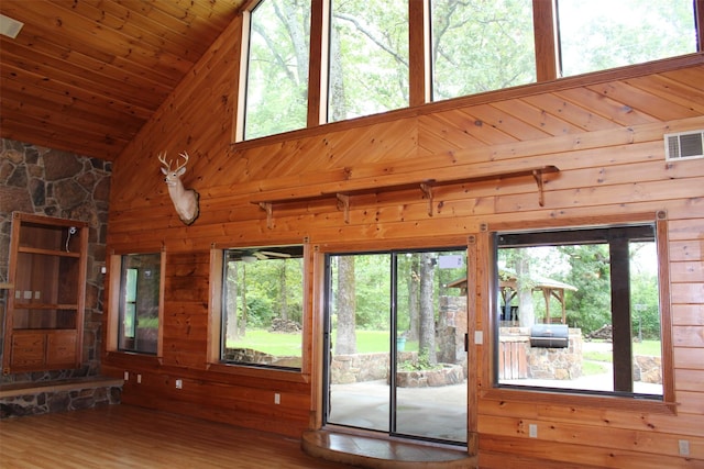 unfurnished living room with hardwood / wood-style floors, a wealth of natural light, wooden ceiling, and wood walls