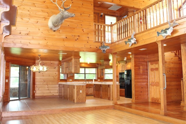 kitchen with plenty of natural light, wooden walls, a kitchen island, and black appliances