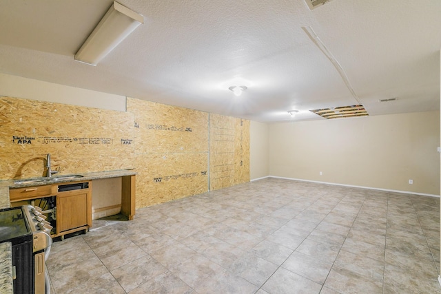 basement with sink, light tile patterned floors, and a textured ceiling