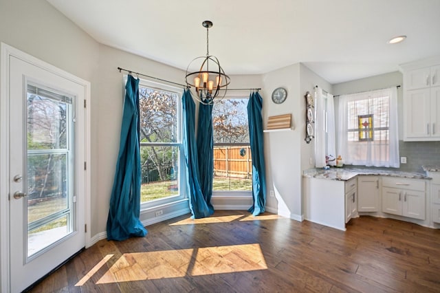 unfurnished dining area with dark hardwood / wood-style flooring and an inviting chandelier