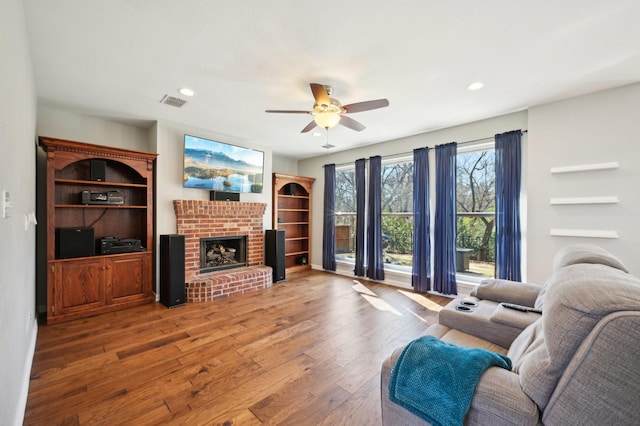 living room featuring hardwood / wood-style flooring, ceiling fan, and a fireplace