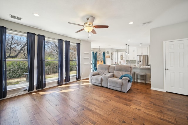 unfurnished living room with ceiling fan with notable chandelier and hardwood / wood-style floors