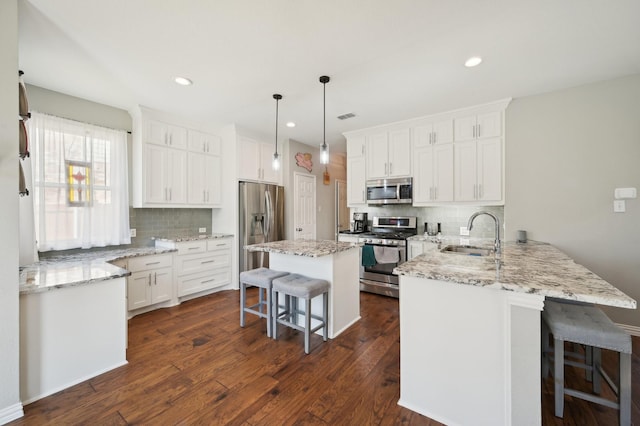 kitchen with white cabinetry, a kitchen breakfast bar, stainless steel appliances, and kitchen peninsula