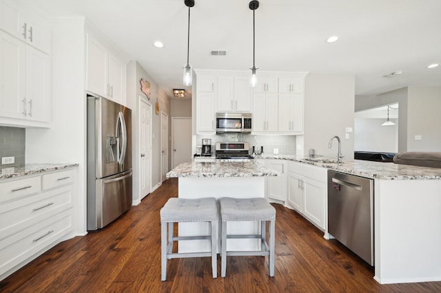 kitchen with dark wood-type flooring, sink, decorative light fixtures, stainless steel appliances, and white cabinets