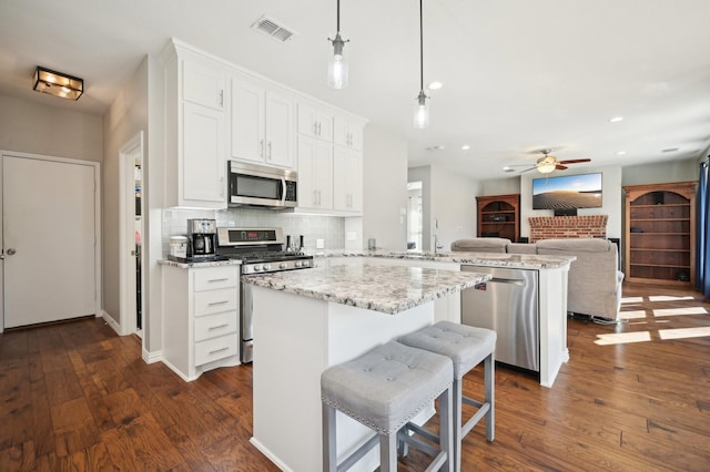 kitchen featuring white cabinetry, decorative light fixtures, appliances with stainless steel finishes, kitchen peninsula, and decorative backsplash