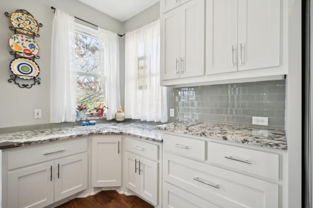 kitchen featuring white cabinetry, light stone counters, and decorative backsplash