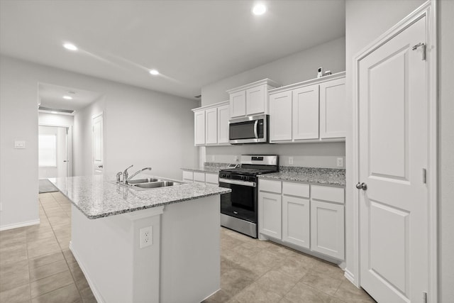 kitchen featuring sink, a center island with sink, appliances with stainless steel finishes, light stone countertops, and white cabinets