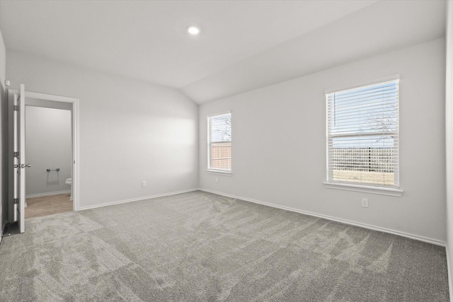 unfurnished room featuring lofted ceiling and carpet flooring