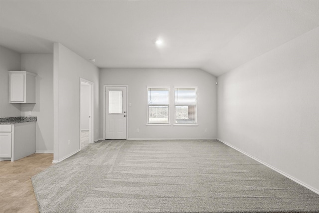 unfurnished living room featuring light carpet and vaulted ceiling