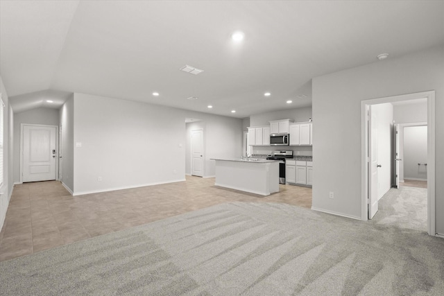 unfurnished living room with vaulted ceiling and light colored carpet