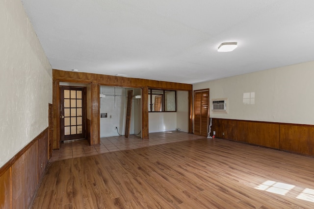 spare room with hardwood / wood-style floors, wooden walls, and a wall unit AC