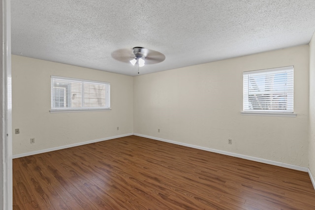 unfurnished room featuring ceiling fan, plenty of natural light, dark hardwood / wood-style floors, and a textured ceiling