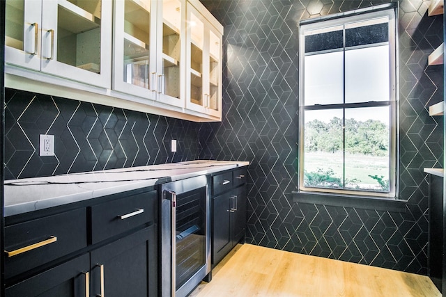 bar with decorative backsplash, beverage cooler, light hardwood / wood-style floors, and tile walls