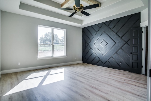 empty room featuring ceiling fan, a raised ceiling, and light hardwood / wood-style flooring