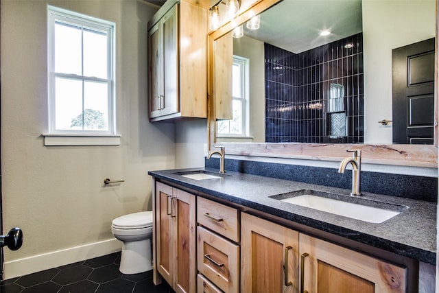 bathroom with tile patterned flooring, vanity, tiled shower, and toilet