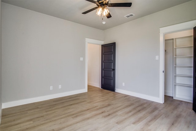 unfurnished bedroom featuring a spacious closet, light hardwood / wood-style flooring, a closet, and ceiling fan