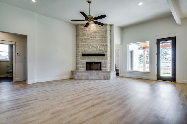 unfurnished living room with light hardwood / wood-style flooring, ceiling fan, a fireplace, and a healthy amount of sunlight