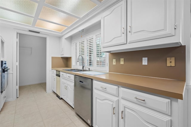 kitchen with light tile patterned floors, sink, dishwasher, white cabinets, and oven