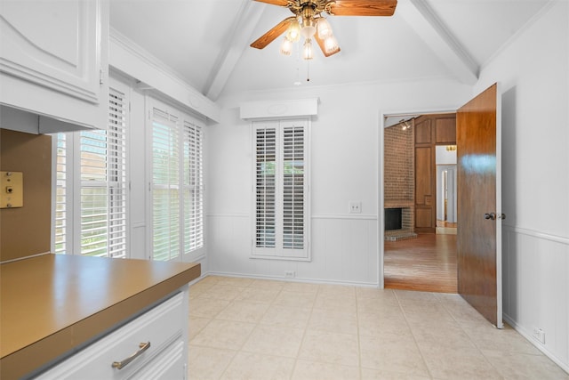 interior space featuring light tile patterned flooring, ceiling fan, lofted ceiling with beams, and a brick fireplace