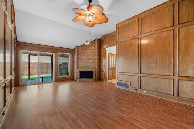 unfurnished living room with ceiling fan, lofted ceiling, light wood-type flooring, and a fireplace