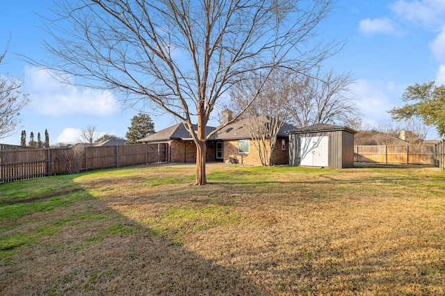 view of yard with a fenced backyard, a storage unit, and an outbuilding