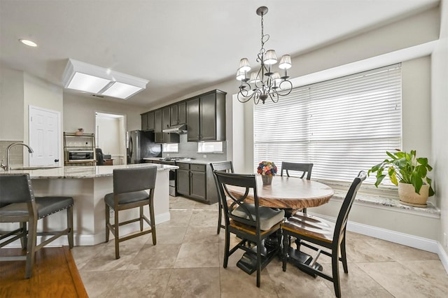 dining area featuring sink, a notable chandelier, and light tile patterned floors