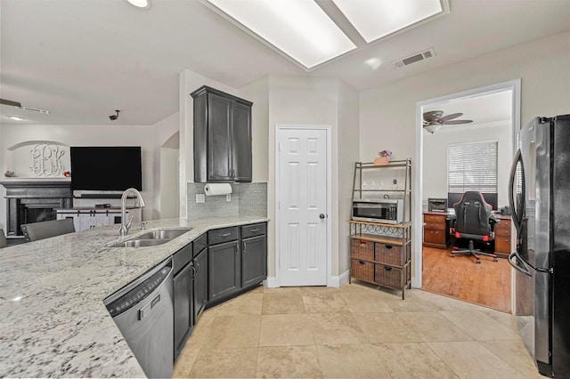 kitchen with sink, ceiling fan, stainless steel appliances, tasteful backsplash, and light stone countertops