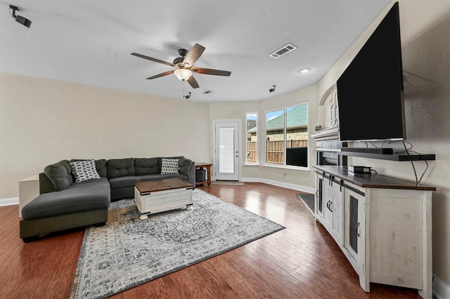 living room featuring ceiling fan and dark wood-type flooring