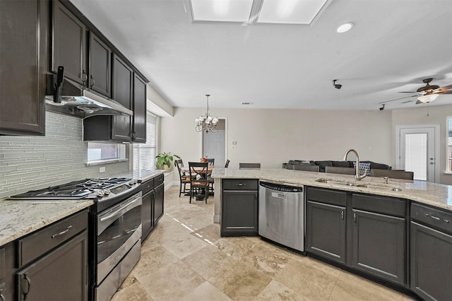 kitchen with sink, appliances with stainless steel finishes, dark brown cabinets, tasteful backsplash, and decorative light fixtures