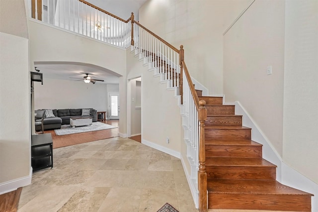 staircase with ceiling fan and a towering ceiling