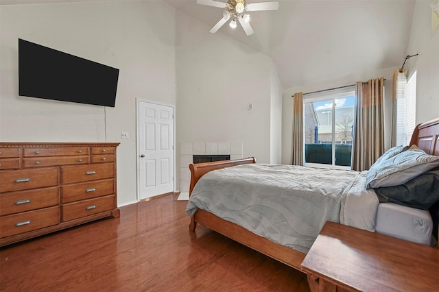 bedroom featuring high vaulted ceiling, access to outside, hardwood / wood-style flooring, ceiling fan, and a fireplace