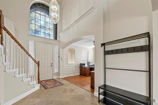 foyer entrance with a high ceiling and ceiling fan with notable chandelier