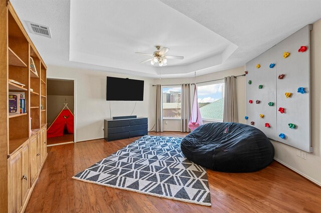 bedroom with a raised ceiling, ceiling fan, and dark hardwood / wood-style flooring