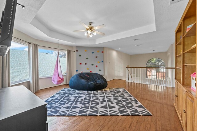 bedroom with ceiling fan, wood-type flooring, and a tray ceiling