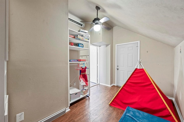 game room with an AC wall unit, ceiling fan, vaulted ceiling, and dark wood-type flooring