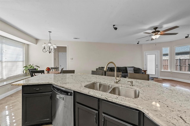 kitchen with dishwasher, light stone countertops, pendant lighting, ceiling fan with notable chandelier, and sink