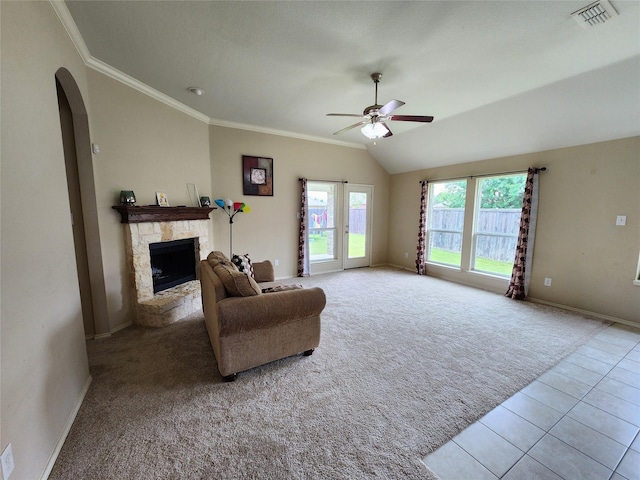 living room featuring vaulted ceiling, light carpet, ornamental molding, ceiling fan, and a fireplace