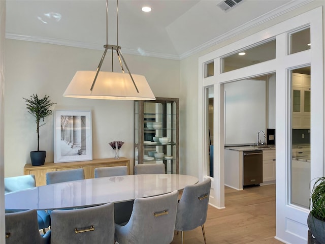 dining space featuring crown molding, sink, and light hardwood / wood-style flooring