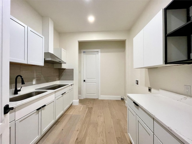 kitchen featuring sink, white cabinetry, backsplash, black electric cooktop, and light wood-type flooring