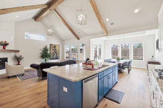 kitchen with dishwasher, blue cabinetry, a center island with sink, and an inviting chandelier