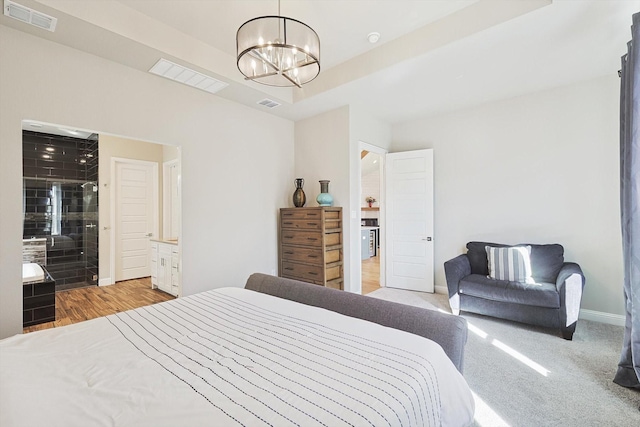 carpeted bedroom with a notable chandelier and a tray ceiling