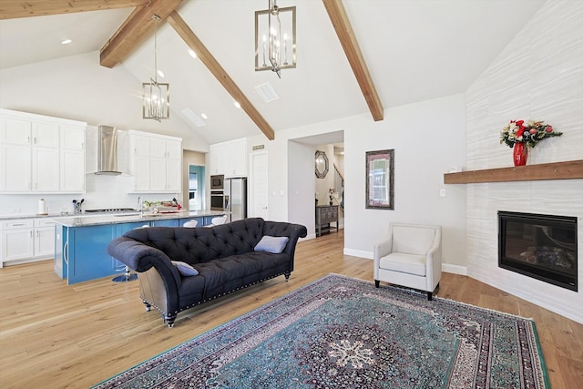 living room featuring a tile fireplace, an inviting chandelier, beam ceiling, high vaulted ceiling, and light hardwood / wood-style floors