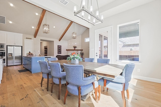 dining room with a notable chandelier, lofted ceiling with beams, and light hardwood / wood-style floors